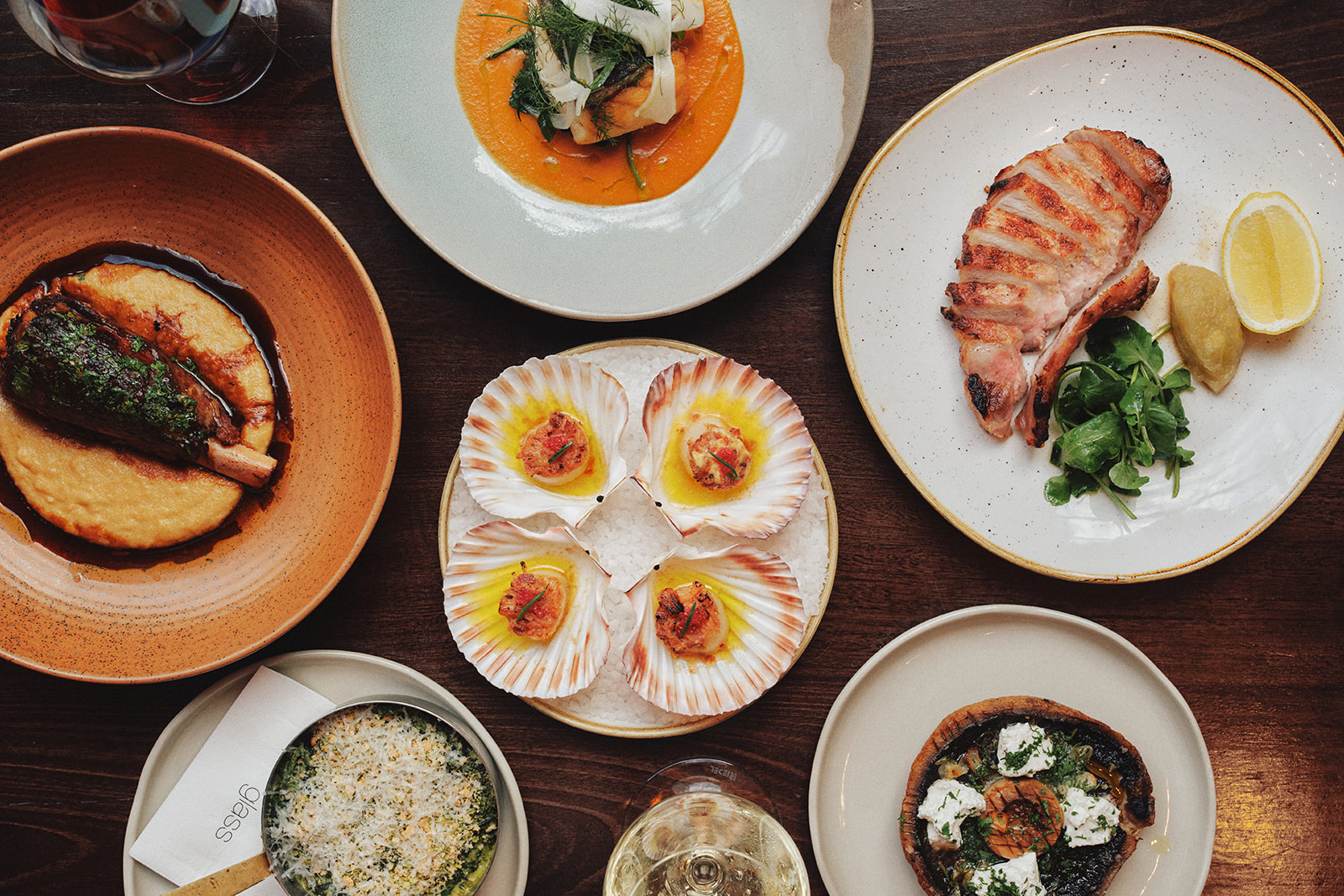 Flat lay of the Glass Brasserie winter menu dishes, including Hokkaido Scallops, 12-hour braised lamb shank and market fish.